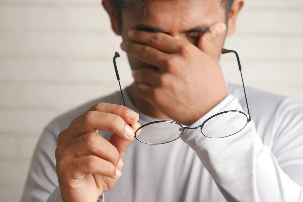 A tired man rubbing his eyes after a poor night of sleep