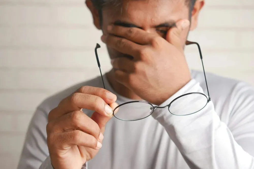 A tired man rubbing his eyes after a poor night of sleep